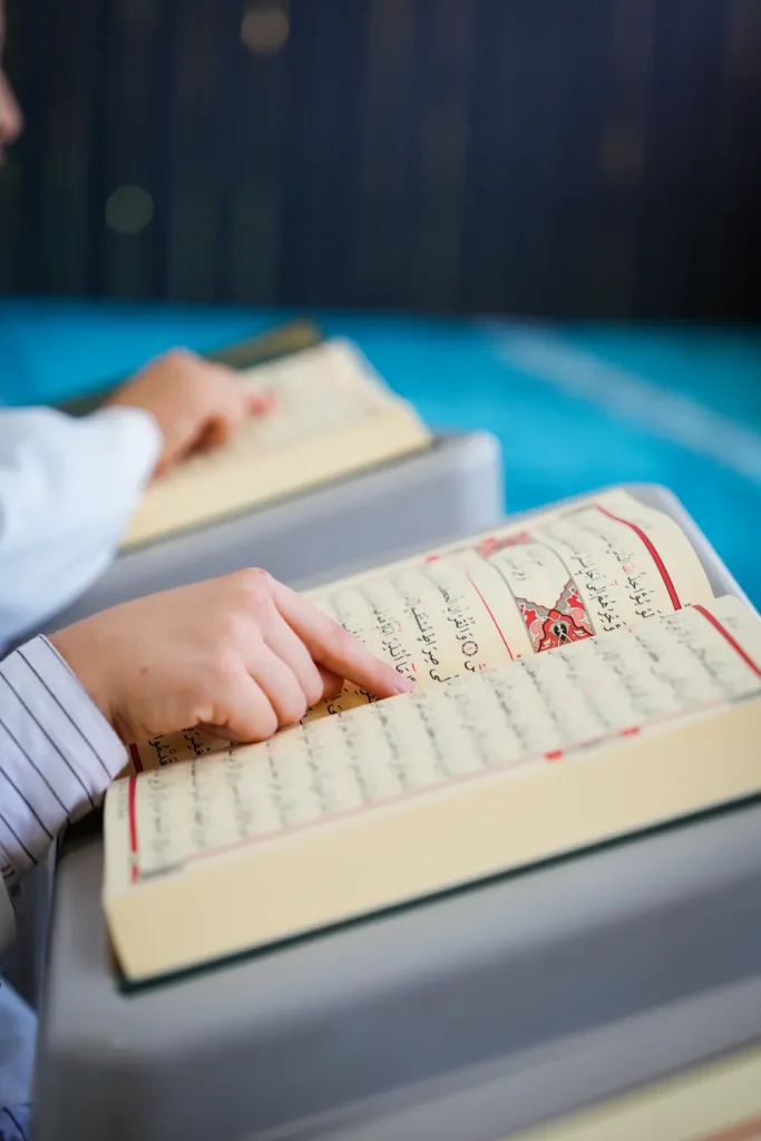 Child pointing at the words while reading the Quran