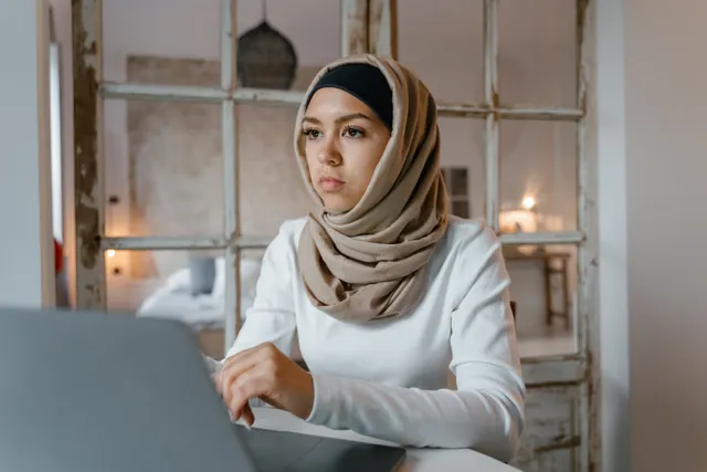 Muslim woman in a hijab learning online on a laptop