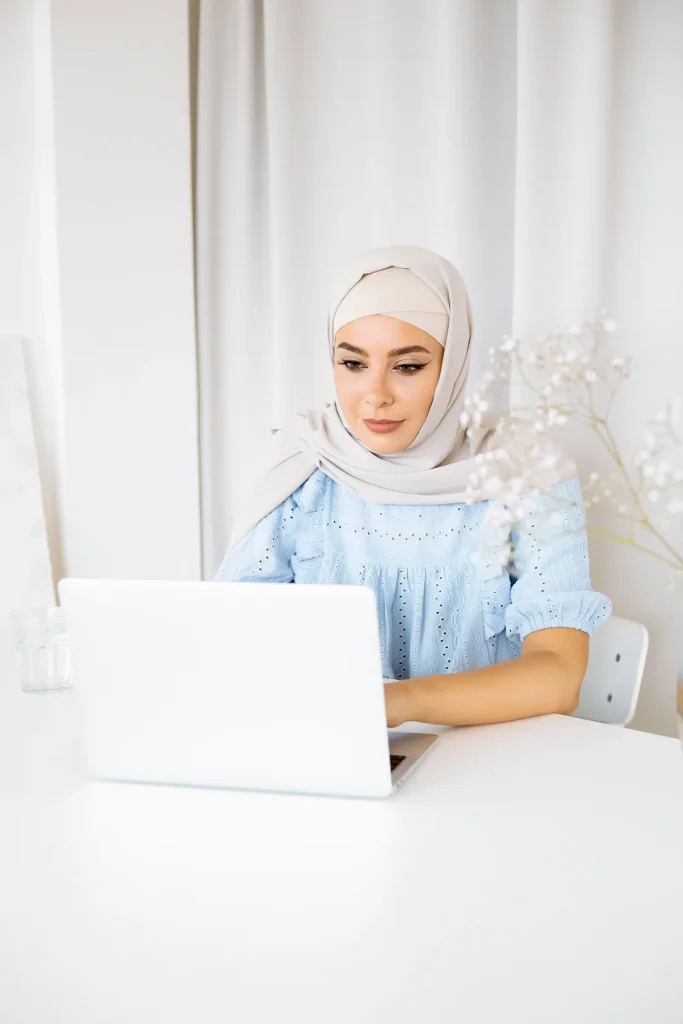 Woman in a hijab taking an online Quran class on a laptop