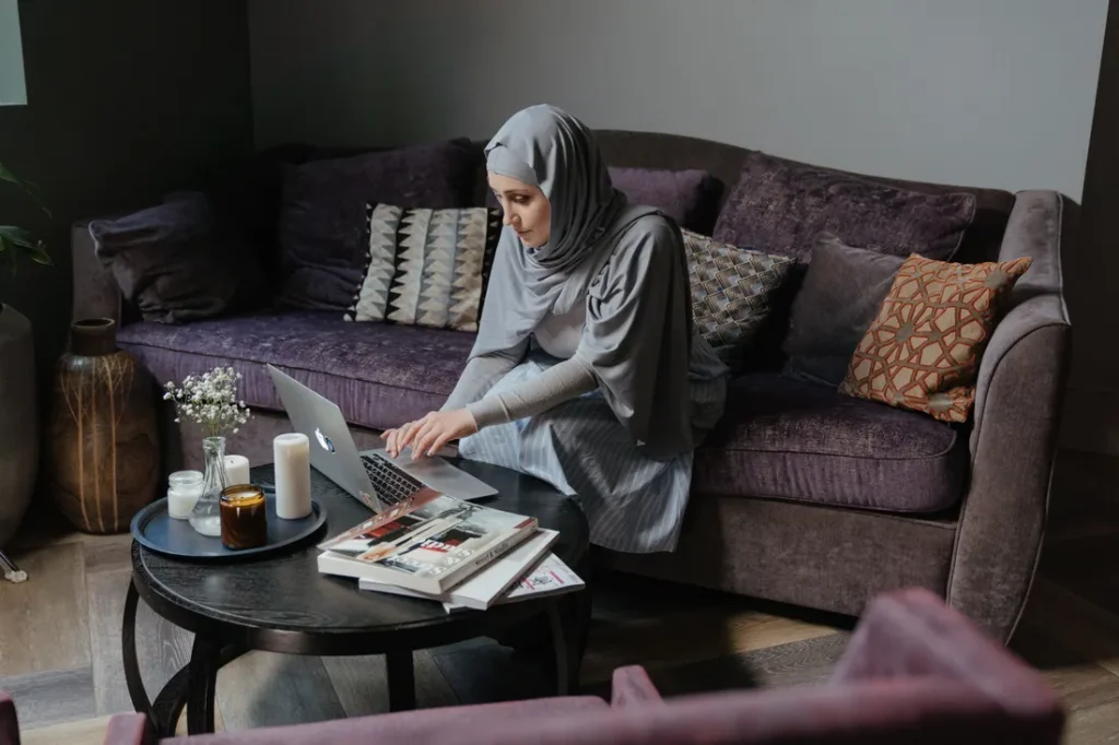 Woman in a hijab joining a free online Quran class from her sofa