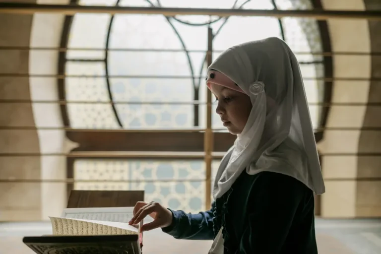 Girl in a hijab reading the Quran on a stand