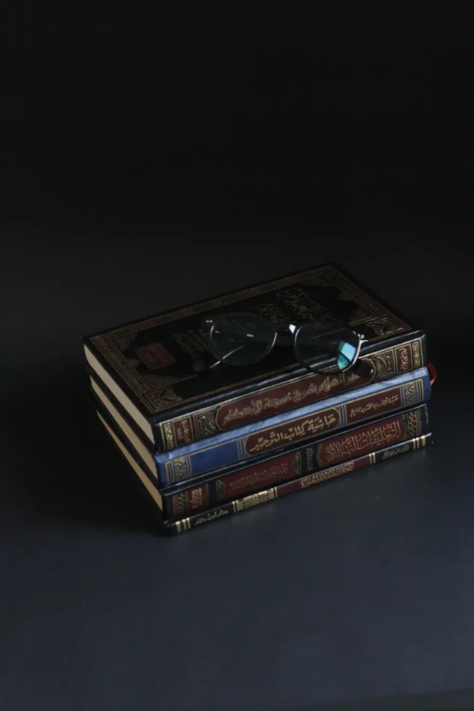 Stacked Islamic books with reading glasses