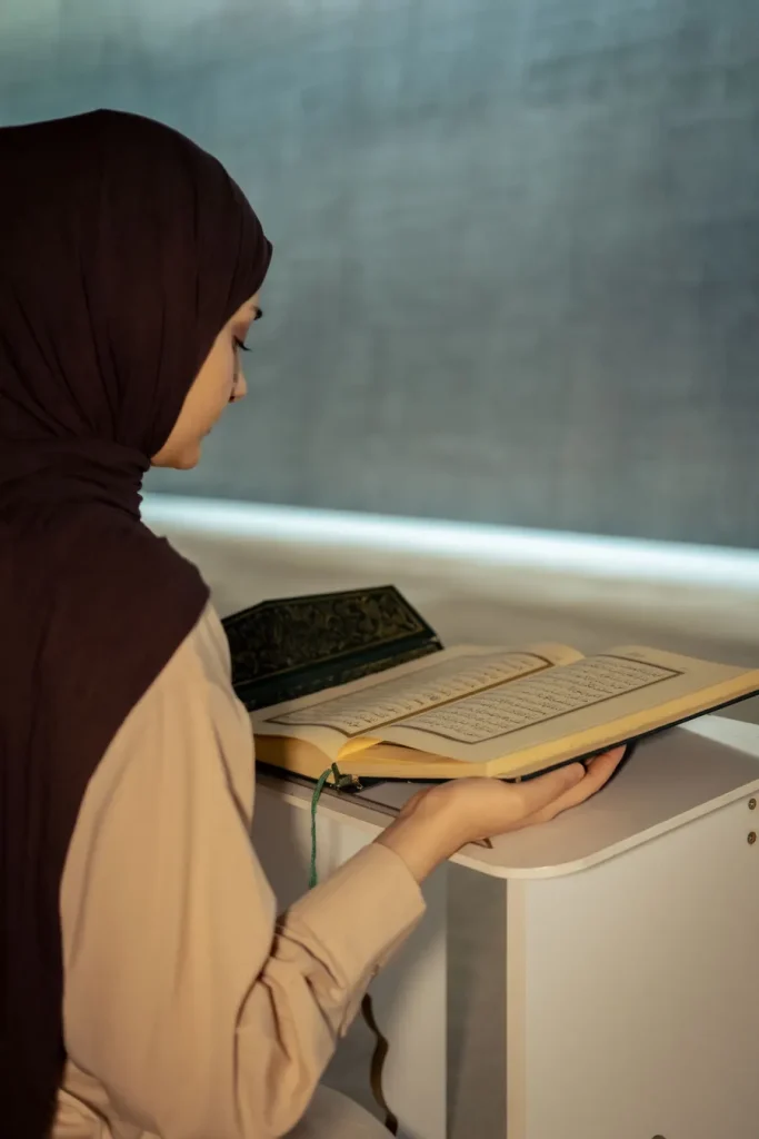 Woman in a hijab reading the Quran on a stand