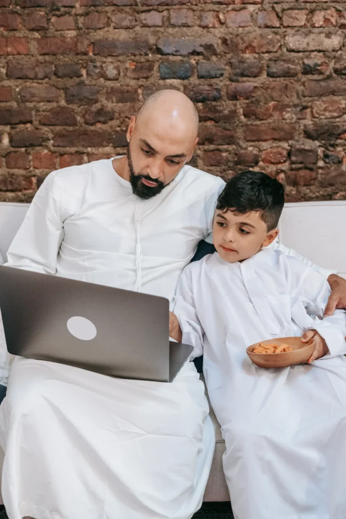 Father and son learning the Quran together on a laptop at home