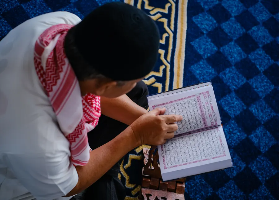 Man following the Quran text with his finger