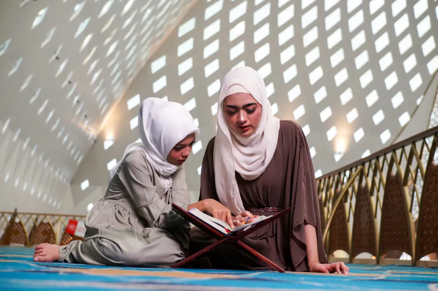 Mother and daughter reading the Quran together in a mosque