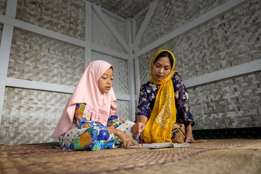 Mother teaching her daughter the Quran at home