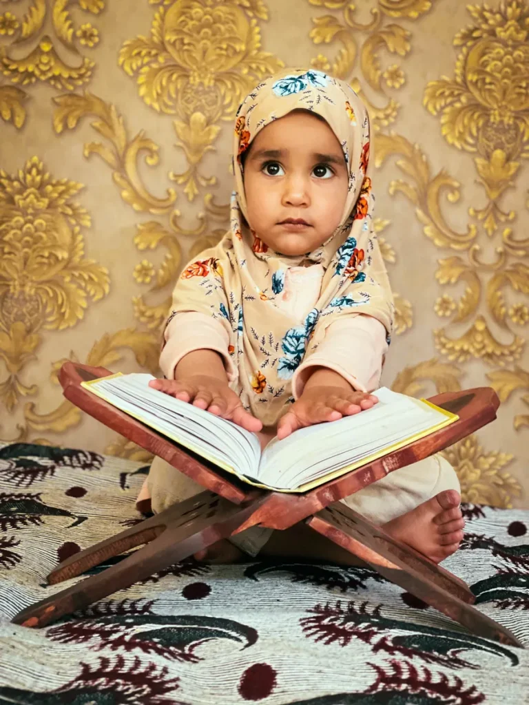 Little girl sitting with a Quran on a wooden stand