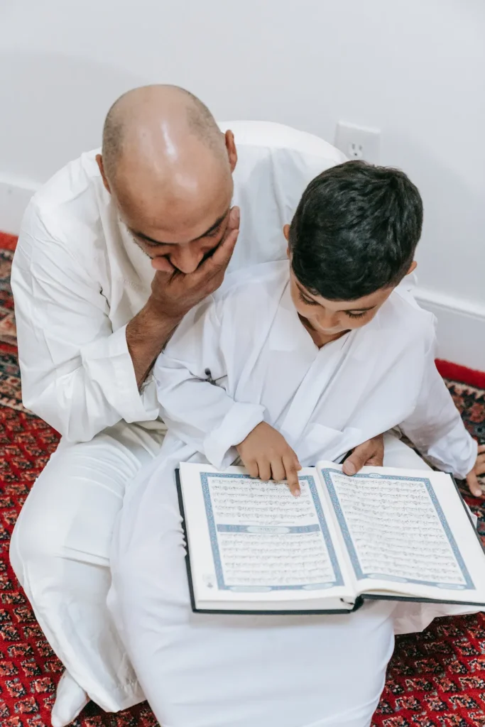 Father teaching his son to read the Quran at home