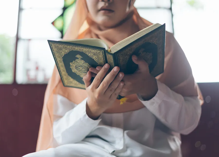 Woman holding an open Quran while reading