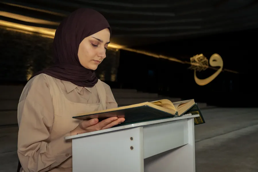 Woman reading the Quran on a stand in a mosque